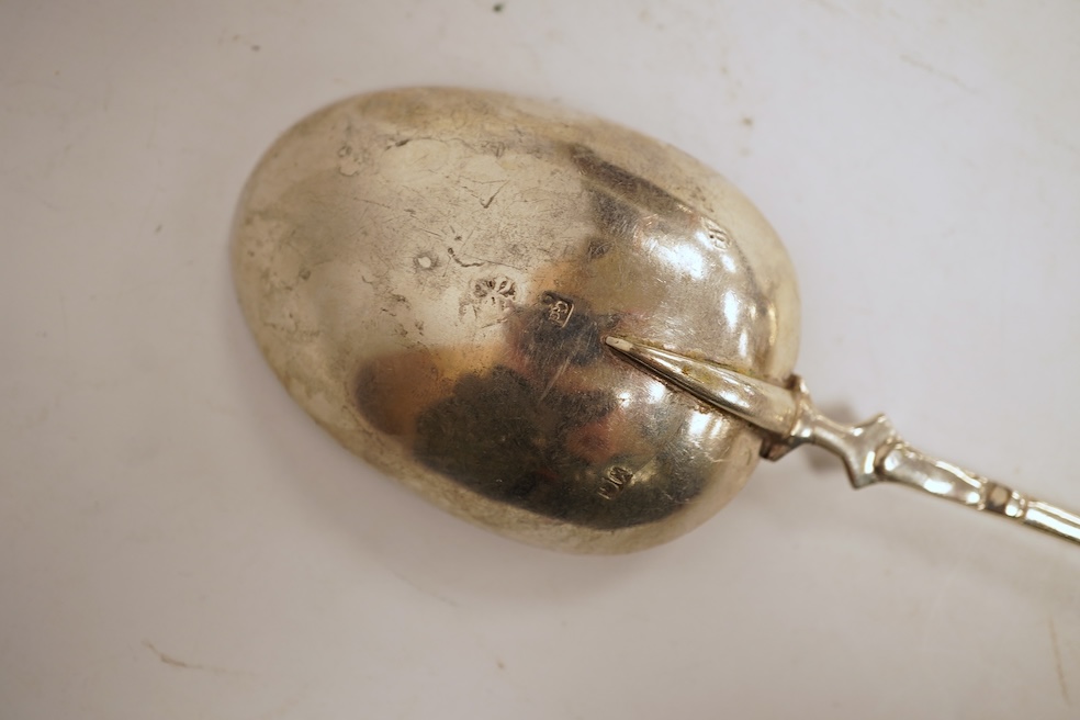 An 18th century silver apostle spoon, indistinct marks, 17cm, a continental white metal spoon with scroll handle and a pair of unmarked white metal spoons with serpent handles.